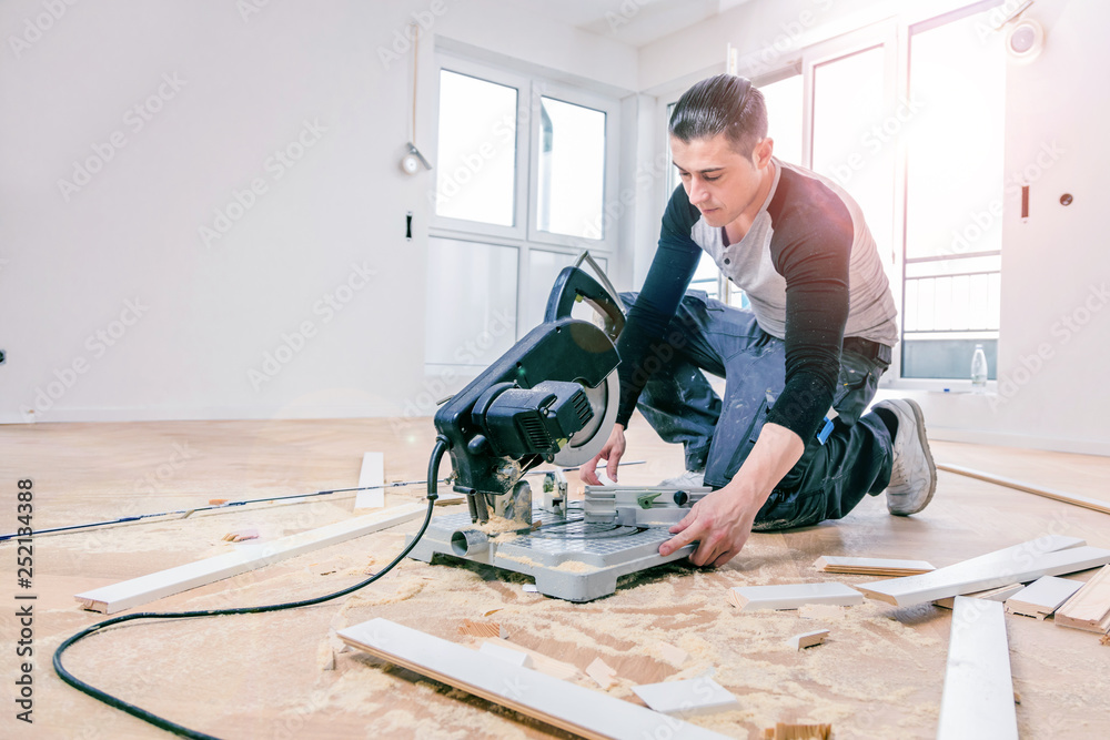 Man with a chop saw cuts skirting boards on a construction site. Lay