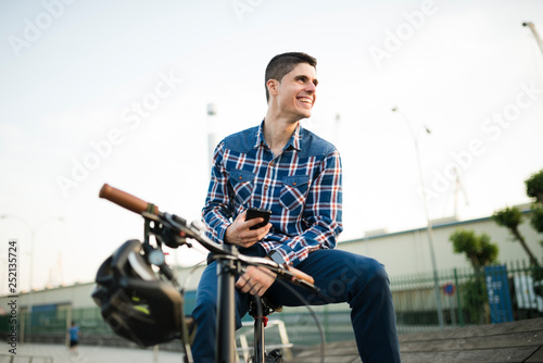 Happy young man with bicycle and cell phone