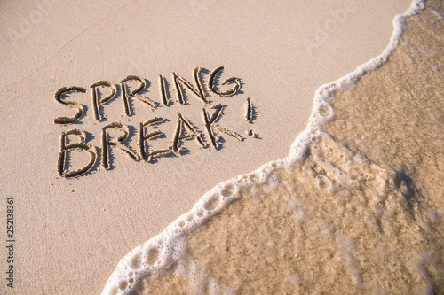Tableau sur toile Excited Spring Break message handwritten on the smooth sand of an empty beach wi