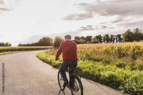 Senior man riding bicycle on country lane photo