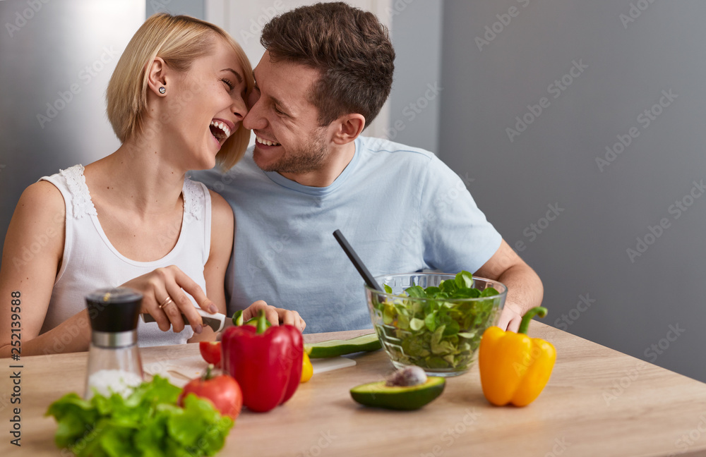 Happy couple making salad at table