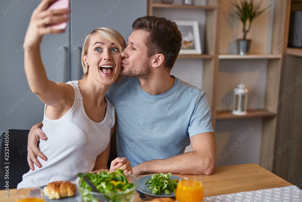 Romantic playful couple taking selfie at table 