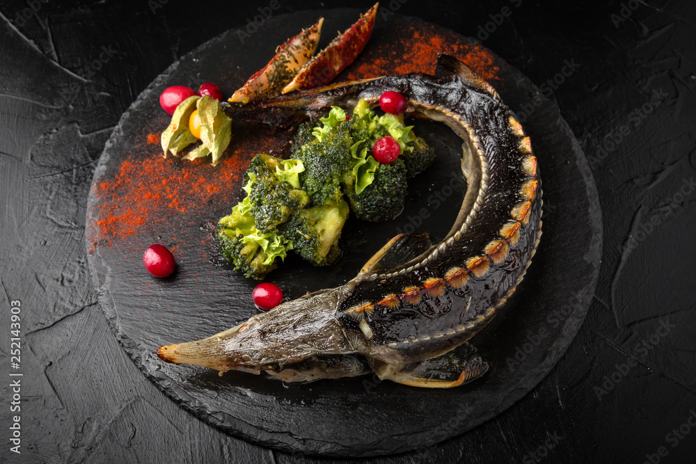 Sterlet baked with vegetables. Grilled sturgeon fish. Healthy food