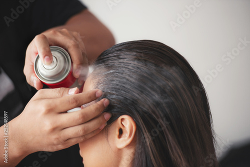 Quadro su tela hairdresser fixing a coiffure with ringlets of a woman using a hair spray in a b