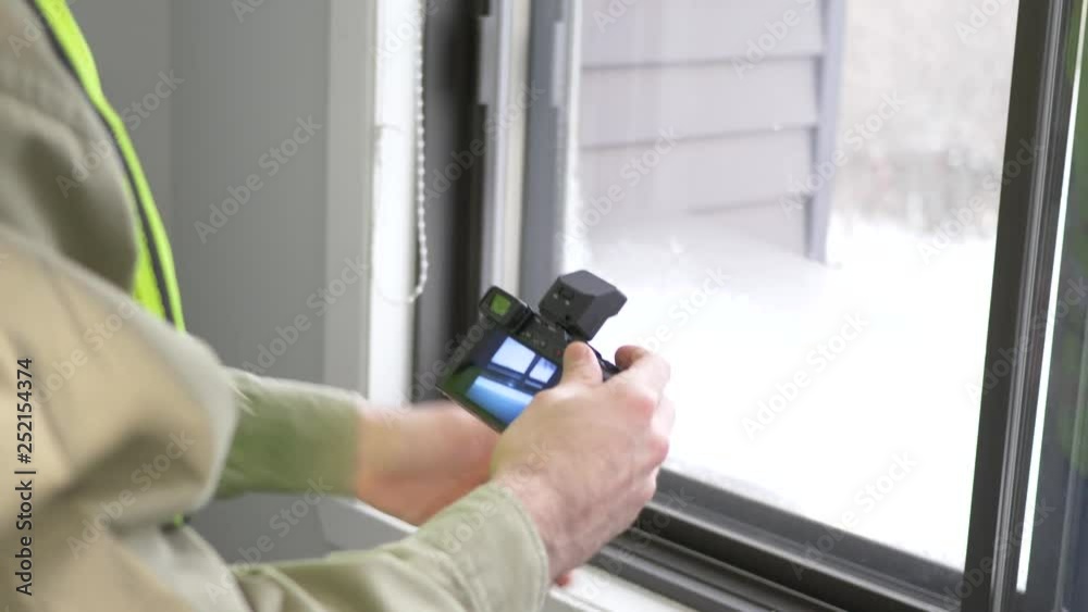 Home inspector taking photographs with a camera around a window where the heat is loss. Home inspector taking photographs with a camera around a window where the heat is loss.