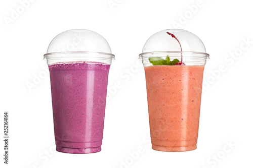 Delicious fruit smoothies in plastic cups, on a white background. Two cocktails with the taste of wild berries and cherries.