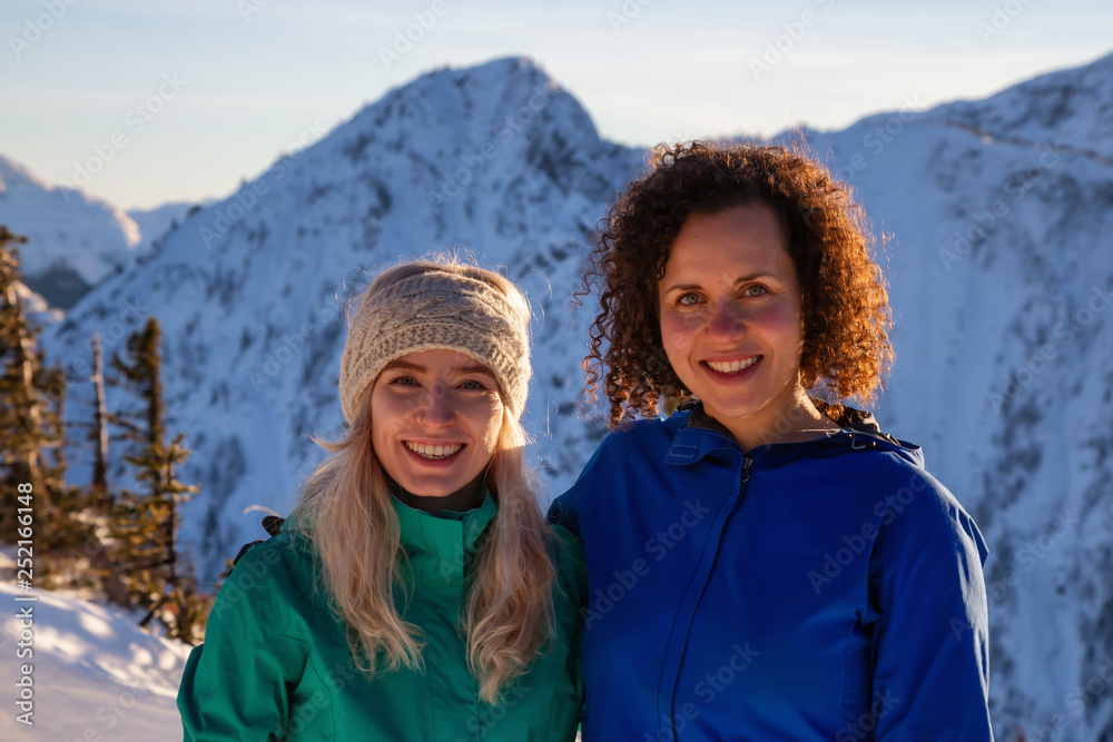 Couple friends are having fun on top of a mountain during a vibrant winter sunset. Taken on top of Zoa Peak near Hope, British Columbia, Canada. Couple friends are having fun on top of a mountain during a vibrant winter sunset. Taken on top of Zoa Peak near Hope, British Columbia, Canada.