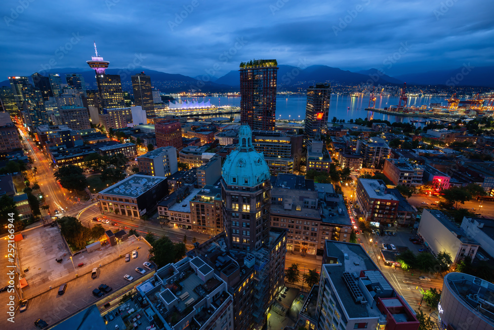 Fototapeta premium Downtown Vancouver, British Columbia, Canada - June 22, 2018: Aerial view of the modern city during night time after a cloudy sunset.