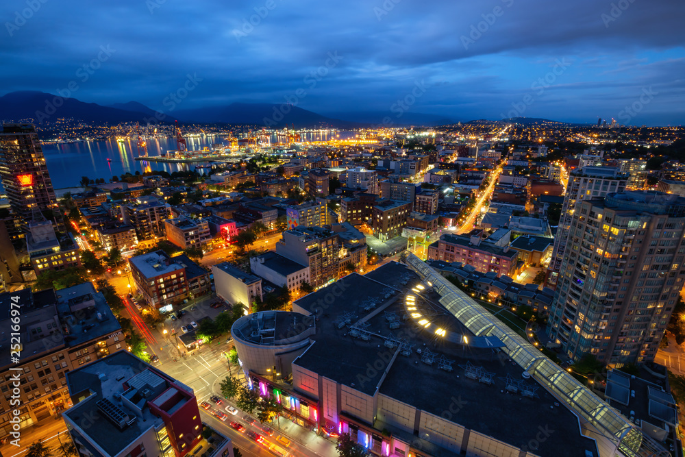Fototapeta premium Downtown Vancouver, British Columbia, Canada - June 22, 2018: Aerial view of the modern city during night time after a cloudy sunset.