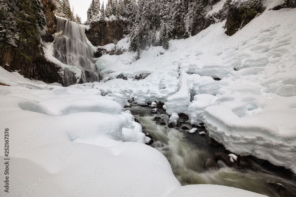 Beautiful Canadian Winter Landscape of the Waterfall during a white snowy day. Taken at Alexander Falls, Near Whistler and Squamish, North of Vancouver, BC, Canada. Beautiful Canadian Winter Landscape of the Waterfall during a white snowy day. Taken at Alexander Falls, Near Whistler and Squamish, North of Vancouver, BC, Canada.