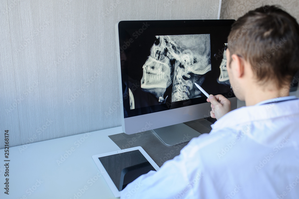 back view of a male radiologist examining neck x-rays (cervical vertebrae) on computer back view of a male radiologist examining neck x-rays (cervical vertebrae) on computer