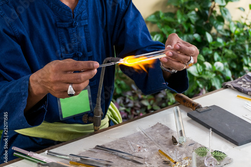 Glassblower burning a pices of glass befor blow to forming shape photo