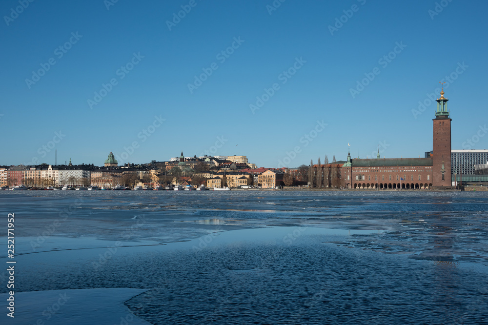 An sunny early spring day in Stockholm, view over a pier with boats and Town City Hall at lake Mälaren