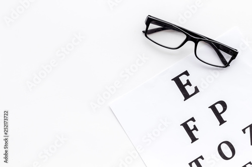 Eye examination. Eyesight test chart and glasses on white background top view space for text