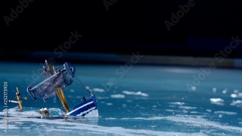 toy fishing trawler is sinking and moving into water in swimming pool, wave is covering