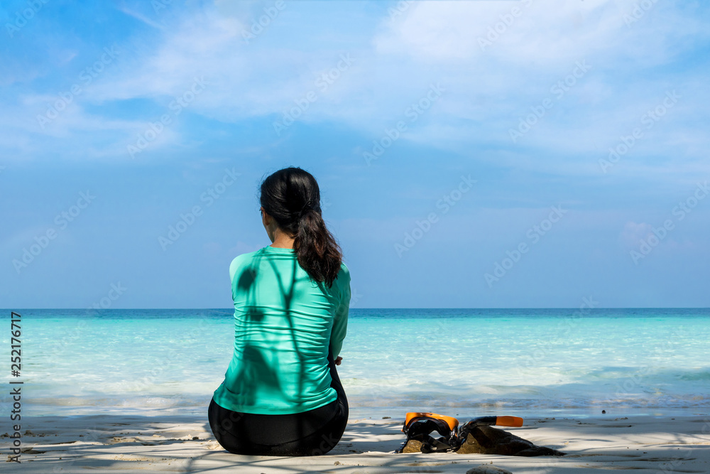 Fototapeta premium Young beautiful woman in swimsuit sitting on white sand beach of andaman sea at summer sunny day