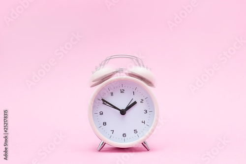 Pink ringing alarm clock on pink background