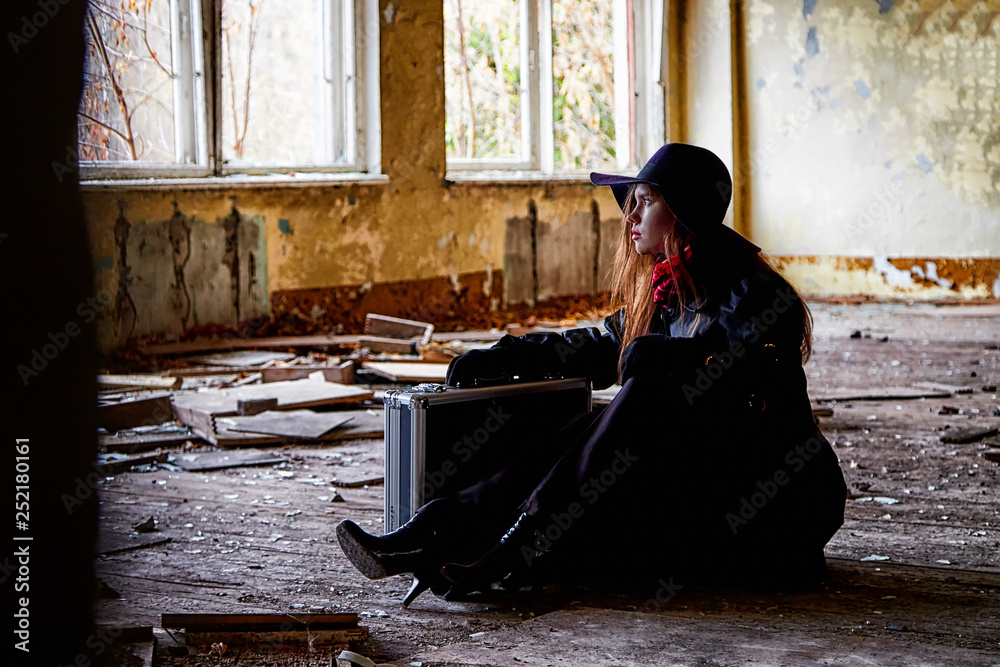 Girl in a black cloak and hat with a diplomat in a ruined room. A spy in a secret meeting. Unusual photo shoot - obrazy, fototapety, plakaty 