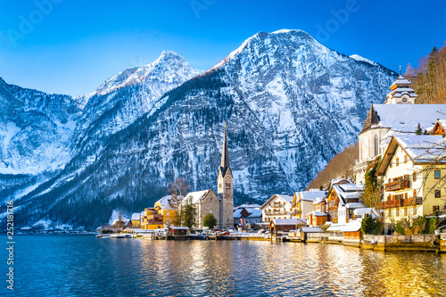 Classic postcard view of famous Hallstatt lakeside town in the Alps with traditional passenger ship on a beautiful cold sunny day with blue sky and clouds in winter, Salzkammergut region, Austria photo