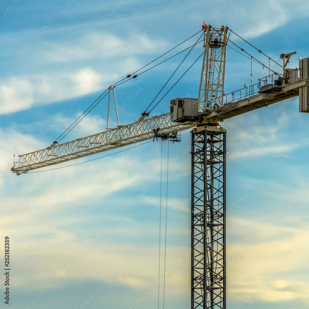 Construction tower crane against bright cloudy sky