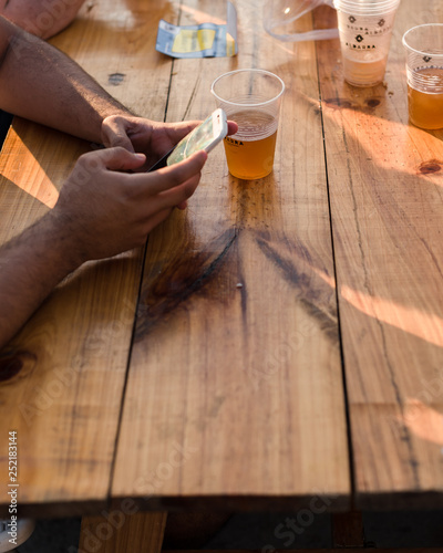 person texting in a table with beer 