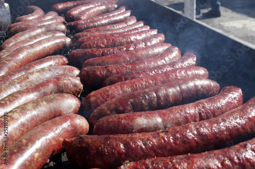 Grilled sausages on bbq. Roasted meat sausages on a barbeque. Fast food outdoor on a grill. Natural light. 