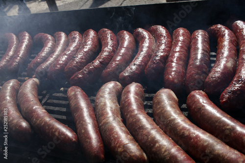 Grilled sausages on bbq. Roasted meat sausages on a barbeque. Fast food outdoor on a grill. Natural light. 