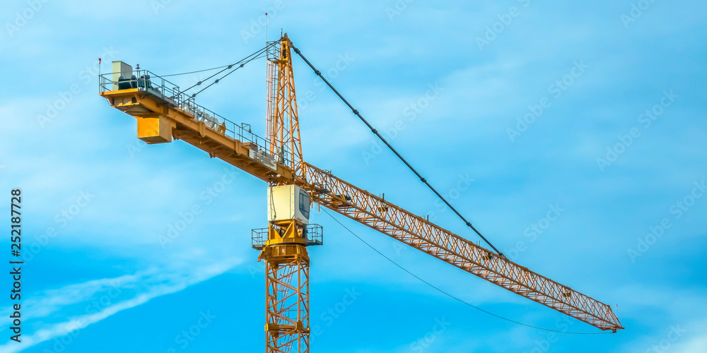 Huge construction tower crane and cloudy blue sky