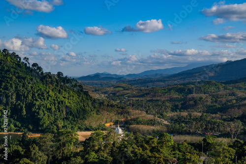 Aerial top view of the green hills valley and white Thai buddhist temple, Nakhon Si Thammarat, Thailand