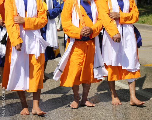 three sikh men with orange clothes during religious ceremony