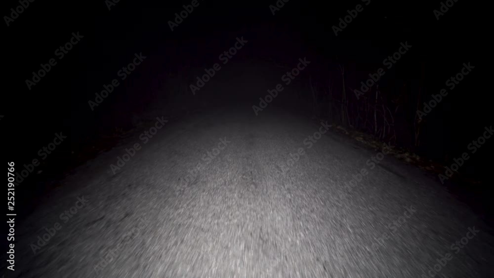 Walking on scary foggy road in complete darkness. Wandering on misty street at night with flashlight illuminating the path ahead. Lost in the dark on empty road in pitch black.