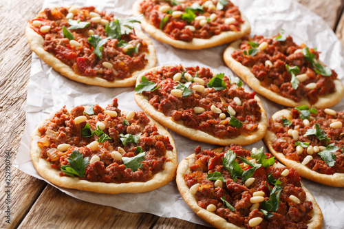 Arab mini pizza with minced meat, tomatoes, onions, spices and pine nuts closeup. horizontal