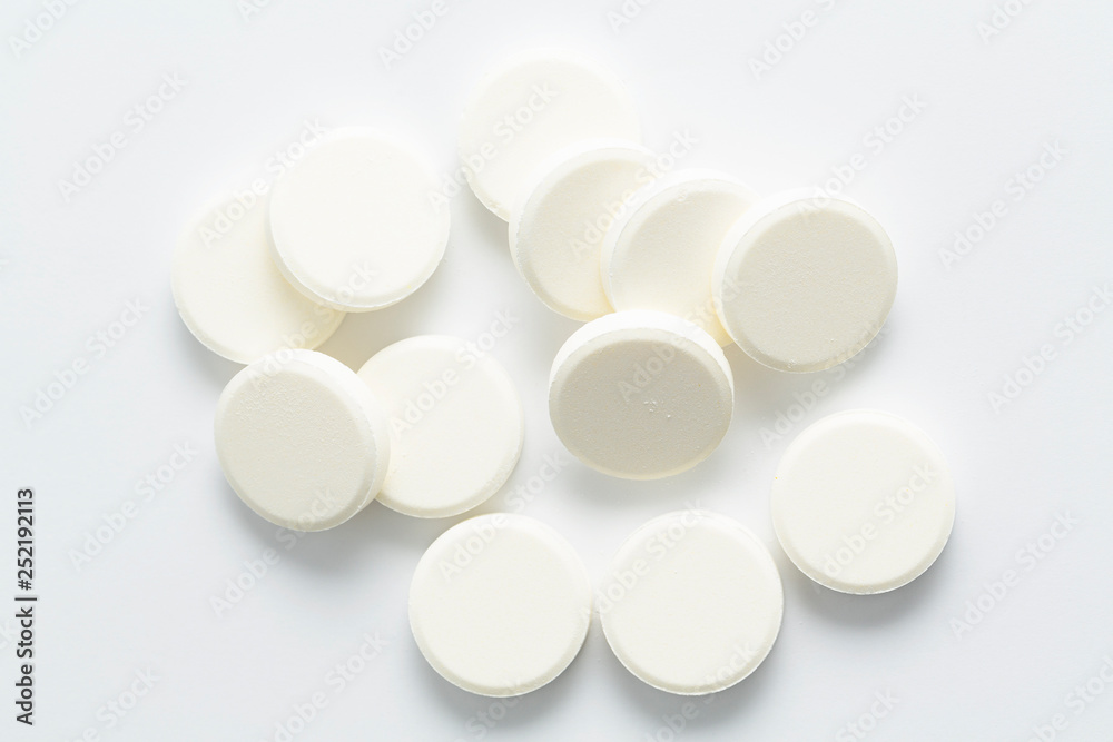 Top view of the Spilled white pills on the white background Top view of the Spilled white pills on the white background