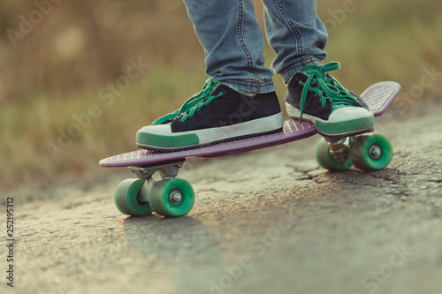 Young happy cute girl rides skateboard on road, outdoor