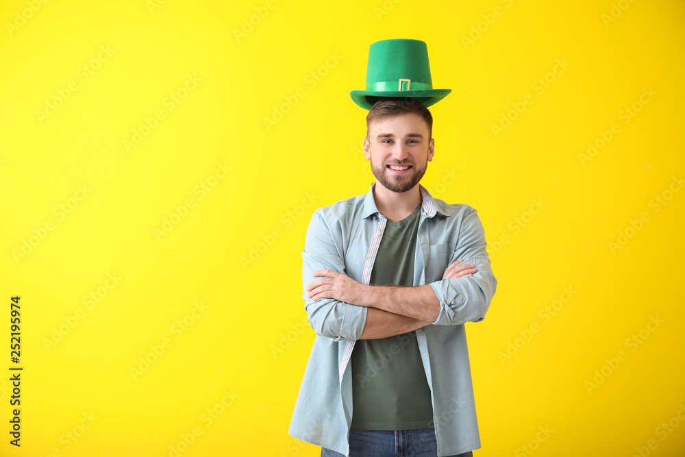 Handsome young man with green hat on color background. St. Patrick's Day celebration