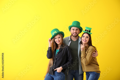 Young people in green hats on color background. St. Patrick's Day celebration