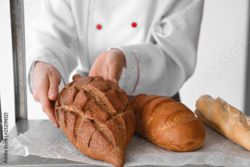 Female chef with freshly baked bread in kitchen