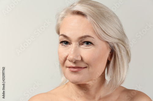 Mature woman with clear skin on light background