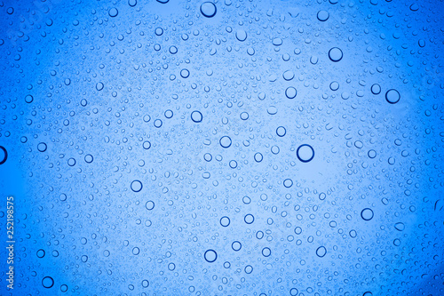 Rain droplets on blue glass background, Water drops on blue glass.