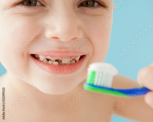 Portrait of little boy with toothbrush on blue background