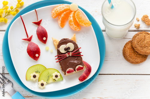 Fun Food for Kids - cute funny cat shaped toast covered with chocolate spread and decorated with fish shaped apple pieces, kiwi slices and tangerines
