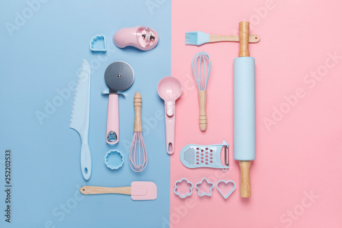 top view of a set of kitchen utensils for baking on pastel pink and blue background