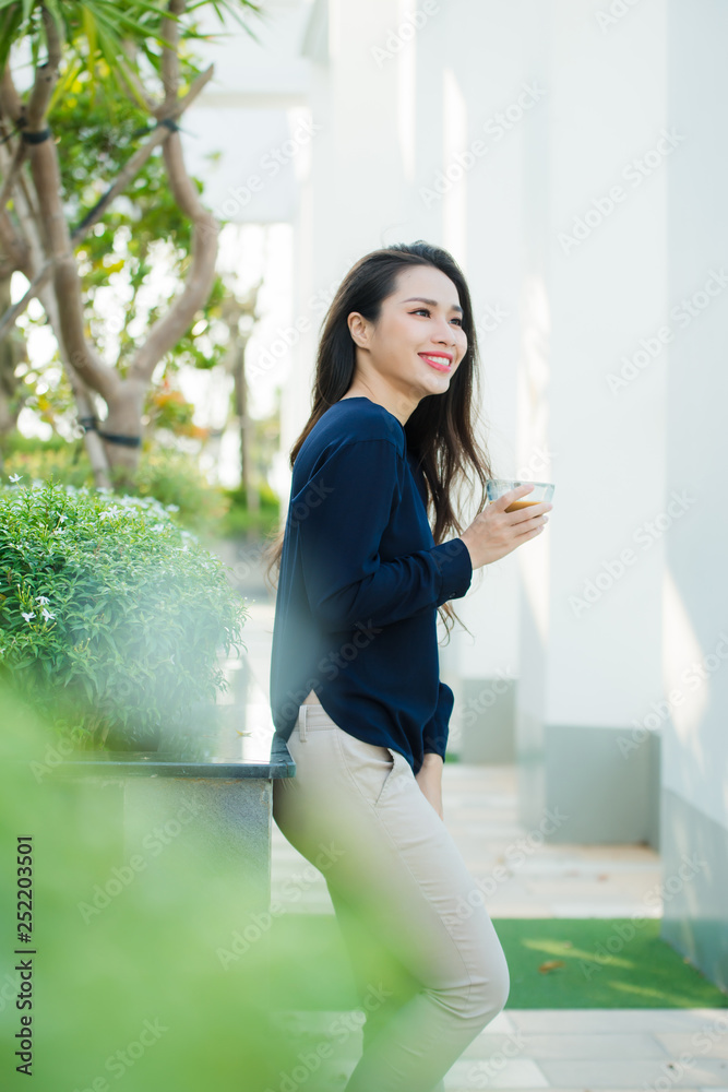 Summer terrace. Woman feeling very relaxed with hand holding glass of coffee while standing on summer terrace Summer terrace. Woman feeling very relaxed with hand holding glass of coffee while standing on summer terrace