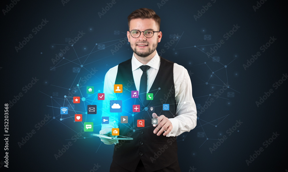 Handsome businessman in suit with tablet on his hand and application icons above
Handsome businessman in suit with tablet on his hand and application icons above