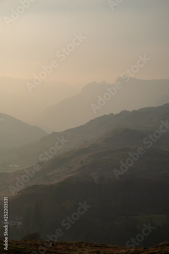 Last light on the Langdale Pikes seen above the Great Langdale valley from the path ascending Loughrigg Fell, Lake District, UK