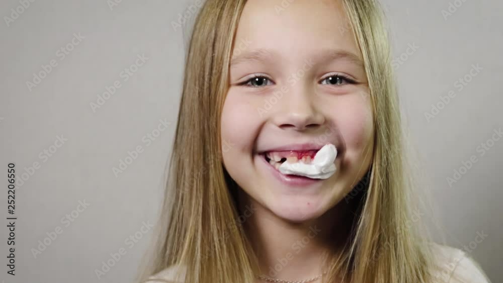 Portrait close-up of a cute smiling girl, a child with a white napkin in his mouth, bleeding gums, jaw. Tooth loss by age concept. 4K resolution Portrait close-up of a cute smiling girl, a child with a white napkin in his mouth, bleeding gums, jaw. Tooth loss by age concept. 4K resolution