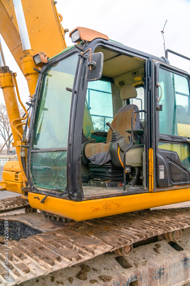 The cab and dirty grousers of a yellow excavator The cab and dirty grousers of a yellow excavator