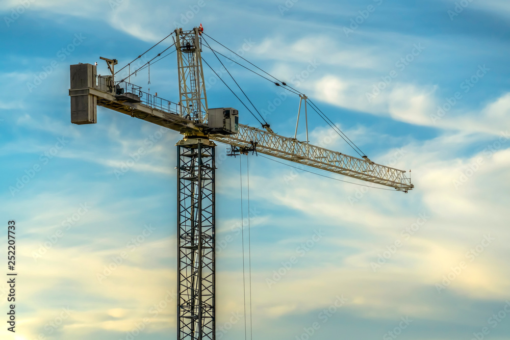 Tower crane at a construction site against sky Tower crane at a construction site against sky