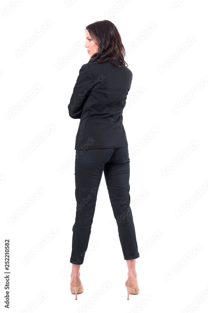 Back view of serious elegant woman in black suit looking away with crossed arms. Full body isolated on white background. Back view of serious elegant woman in black suit looking away with crossed arms. Full body isolated on white background.