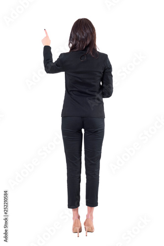 Back view of left handed elegant business woman using touch screen push button. Full body isolated on white background. 